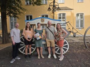 Bild der Teilnehmenden vor der Brühler Kutsche, einem Spielelement in der Nähe des Rathauses